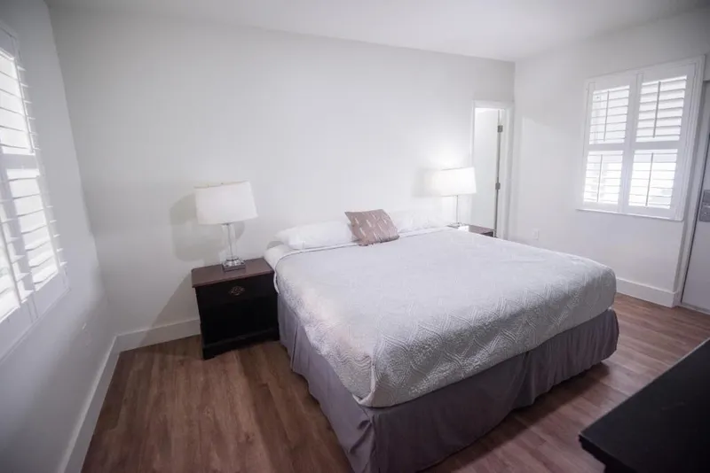 Deluxe room with a queen bed, bedside lamps and shuttered windows