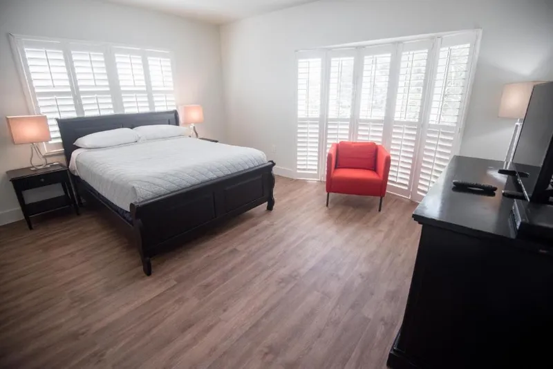 Suite King with a king bed, red armchair and shuttered windows